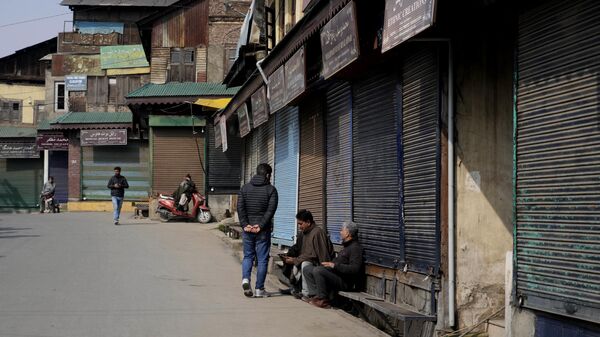 People sit outside closed shops as they spend time in Srinagar, Wednesday, Feb. 15, 2023. - Sputnik India