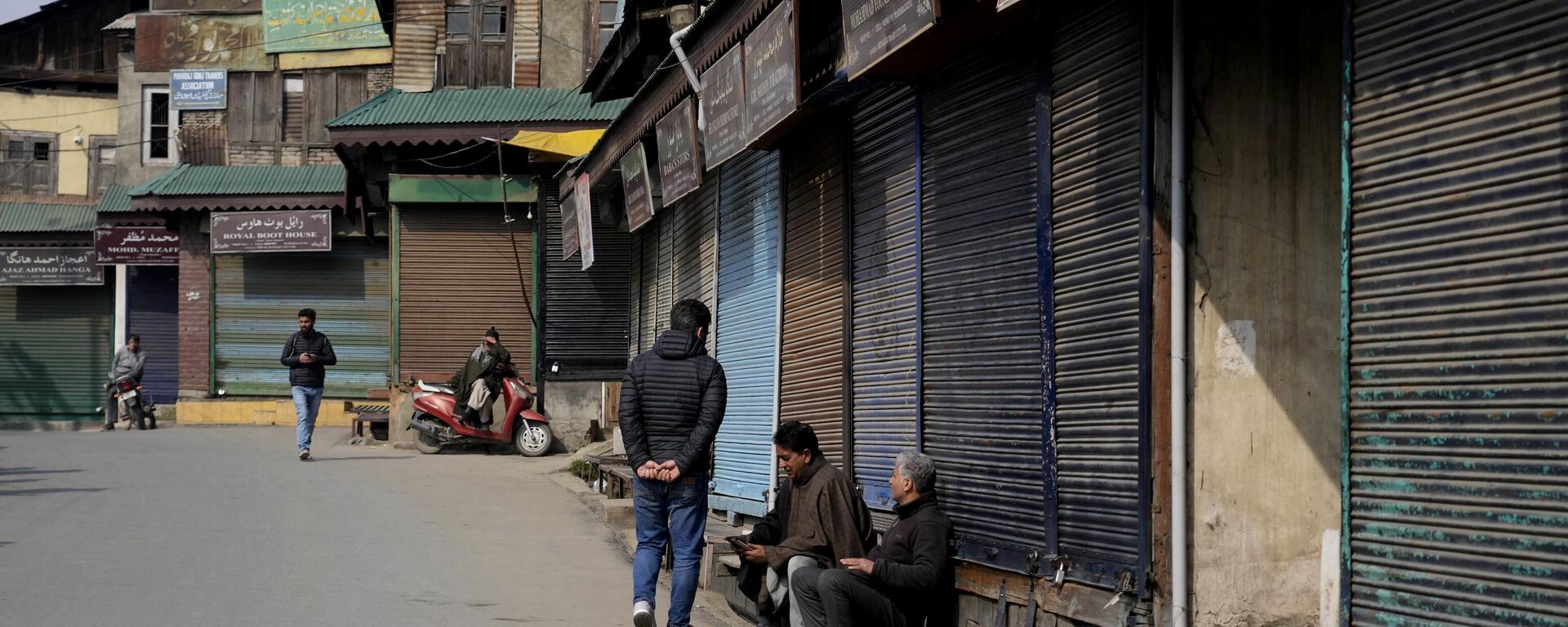 People sit outside closed shops as they spend time in Srinagar, Wednesday, Feb. 15, 2023. - Sputnik India, 1920, 22.02.2023