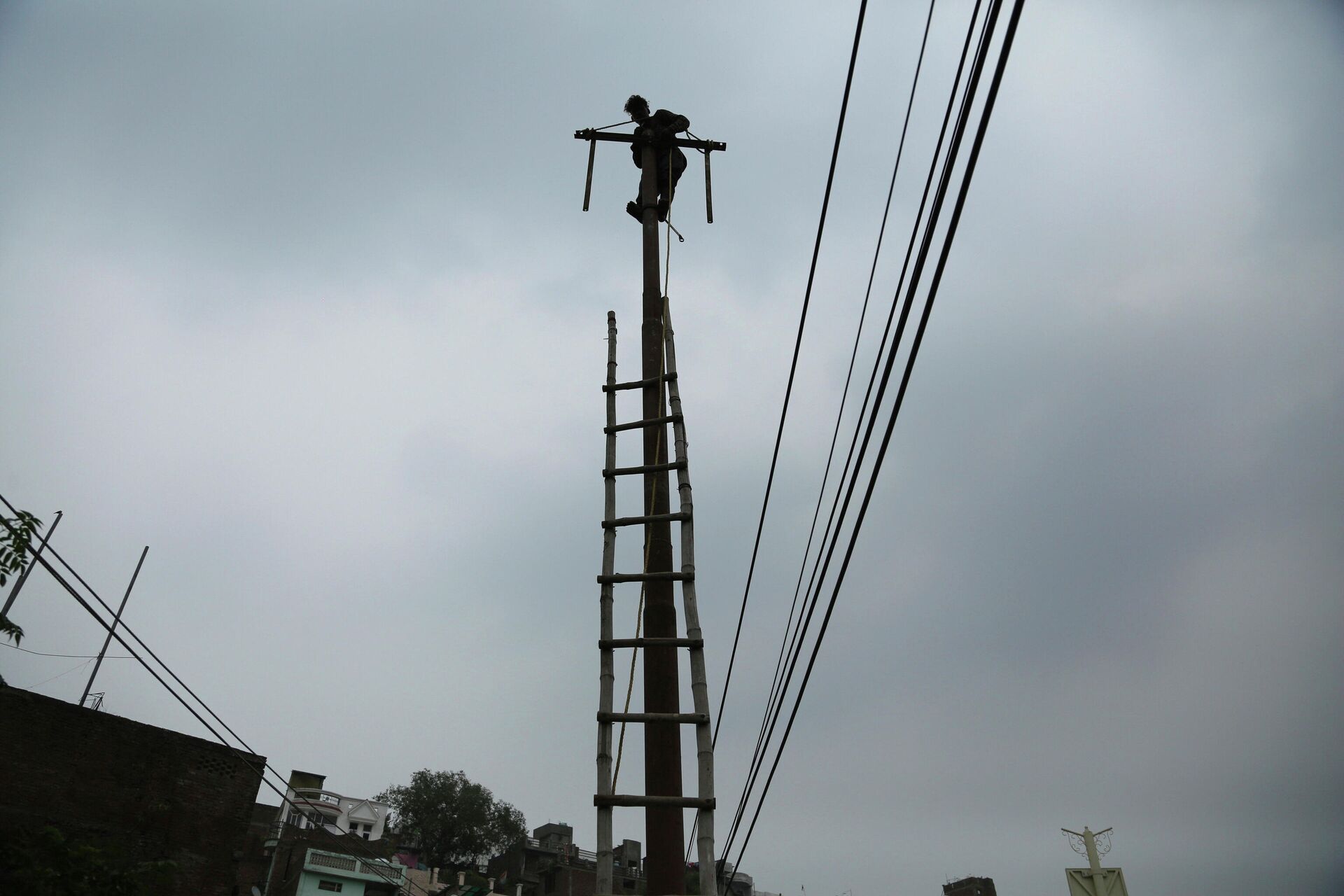 An Indian electricity department worker climbs on a pole to fix power lines as monsoon clouds gather above in Jammu, India, Sunday, July 18, 2021 - Sputnik India, 1920, 02.03.2023