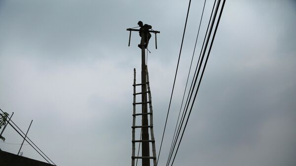 An Indian electricity department worker climbs on a pole to fix power lines as monsoon clouds gather above in Jammu, India, Sunday, July 18, 2021 - Sputnik भारत