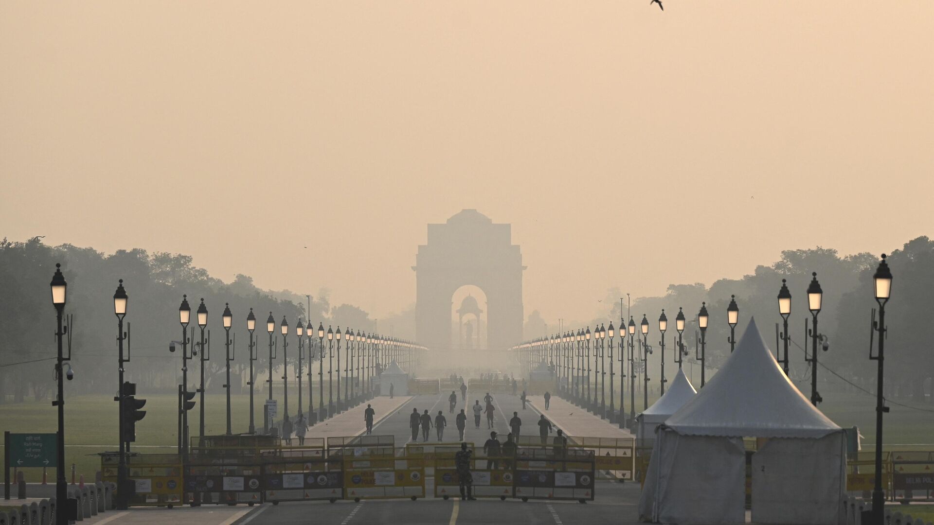 People walk along a road near India Gate amid smoggy conditions in New Delhi on October 25, 2022.  - Sputnik India, 1920, 03.03.2023