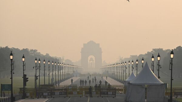 People walk along a road near India Gate amid smoggy conditions in New Delhi on October 25, 2022.  - Sputnik भारत