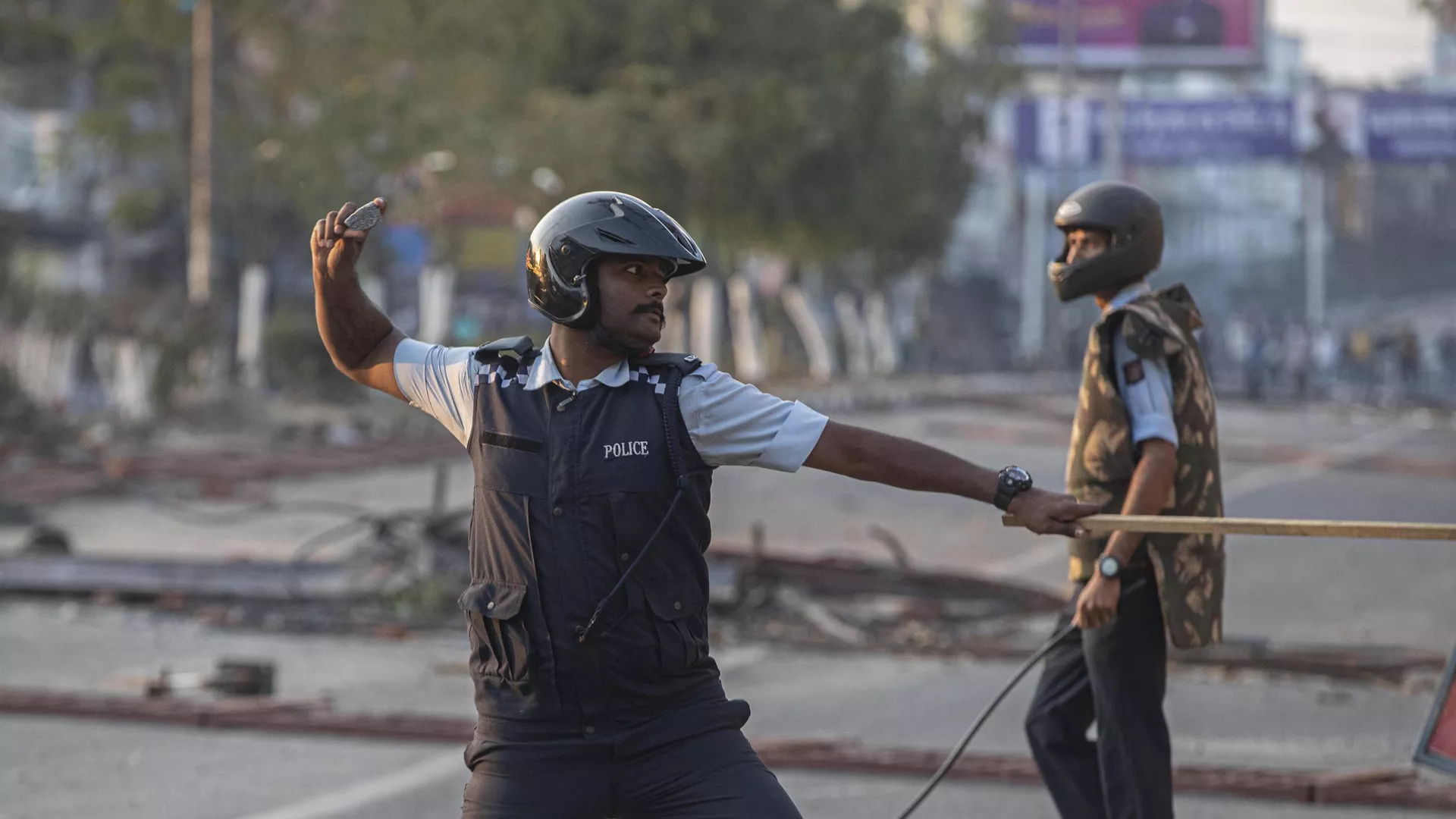 An Indian policeman throws back a stone to protestors.