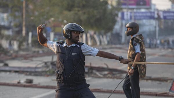 An Indian policeman throws back a stone on stone pelting protestors - Sputnik भारत