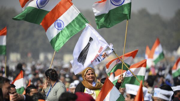 Supporters of the Aam Aadmi Party (AAP) hold party flags and Indian national flags before Arvind Kejriwal swearing-in ceremony as Delhi Chief Minister, in New Delhi on February 16, 2020. - Sputnik India