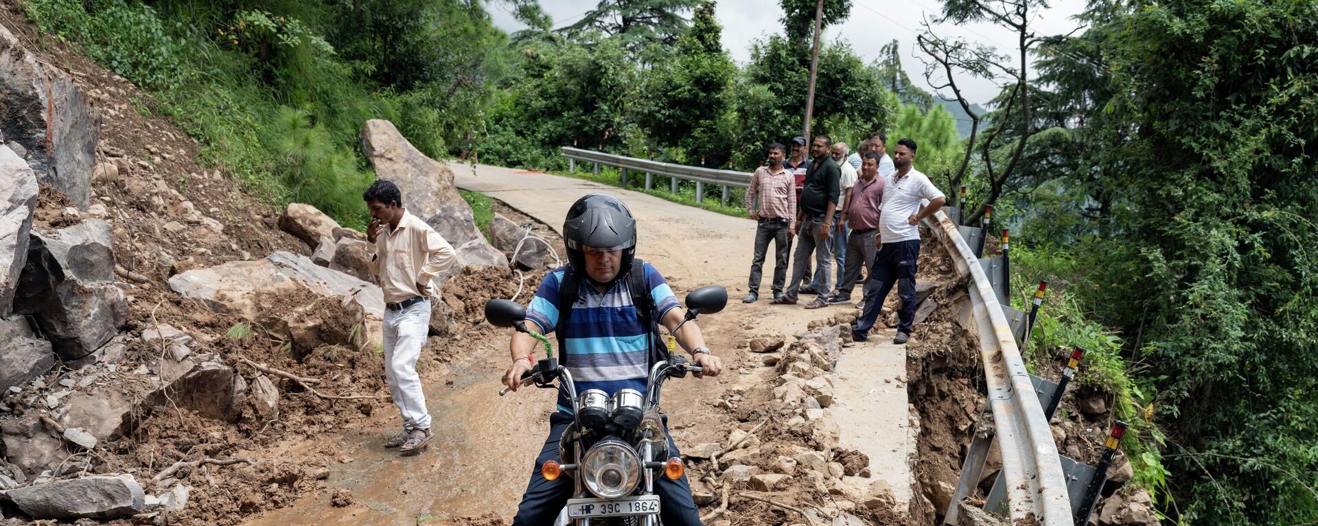 Мотоциклист пытается проехать через перекрытую оползнем дорогу в Дхарамсале, штат Химачал-Прадеш, Индия - Sputnik भारत, 1920, 10.03.2023