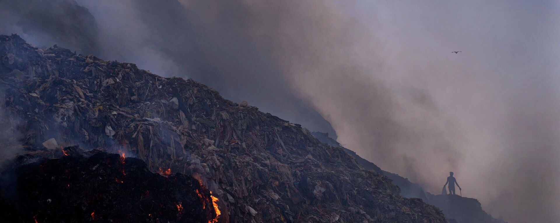 A ragpicker looks for reusable items while a fire rages at the Bhalswa landfill in New Delhi, Wednesday, April 27, 2022 - Sputnik भारत, 1920, 11.03.2023