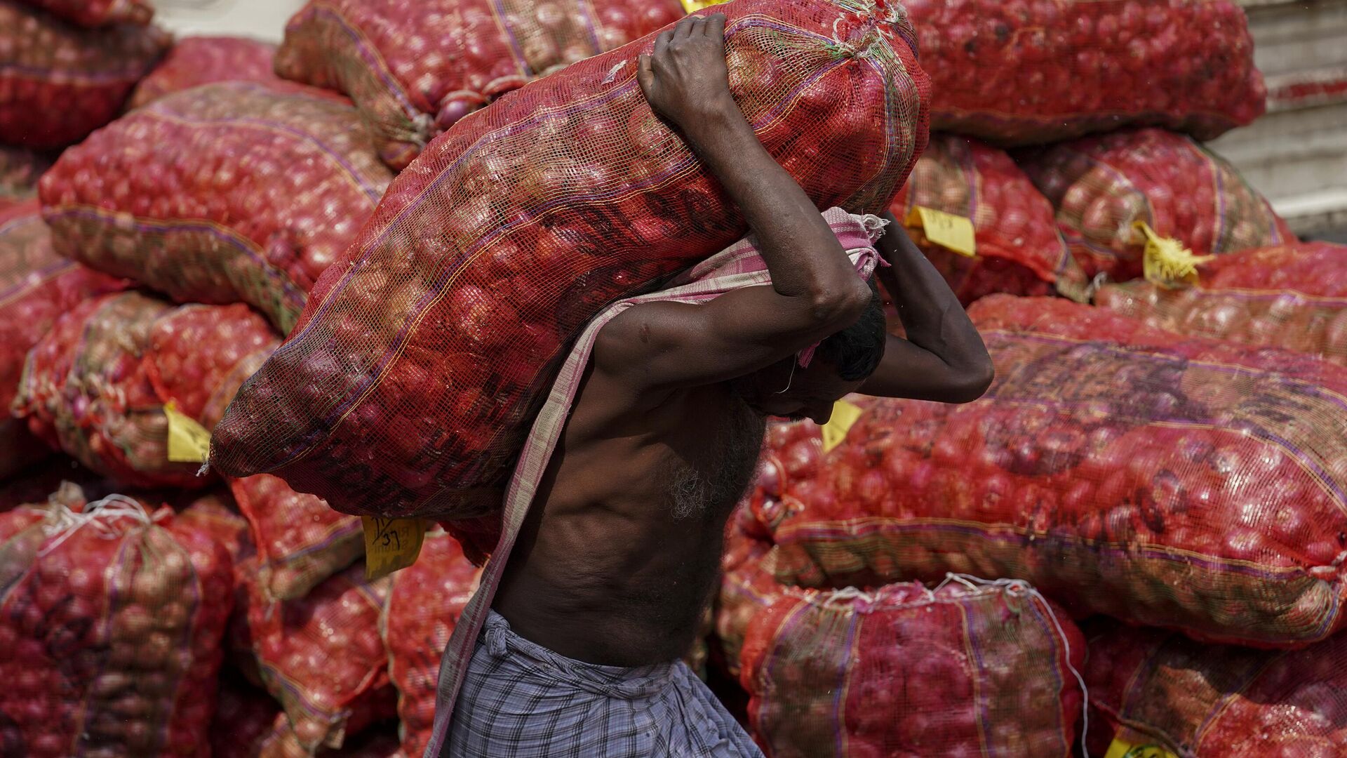 A worker carries a sack of onions at a wholesale market in Hyderabad, India, Wednesday, Feb. 1, 2023. - Sputnik India, 1920, 13.03.2023