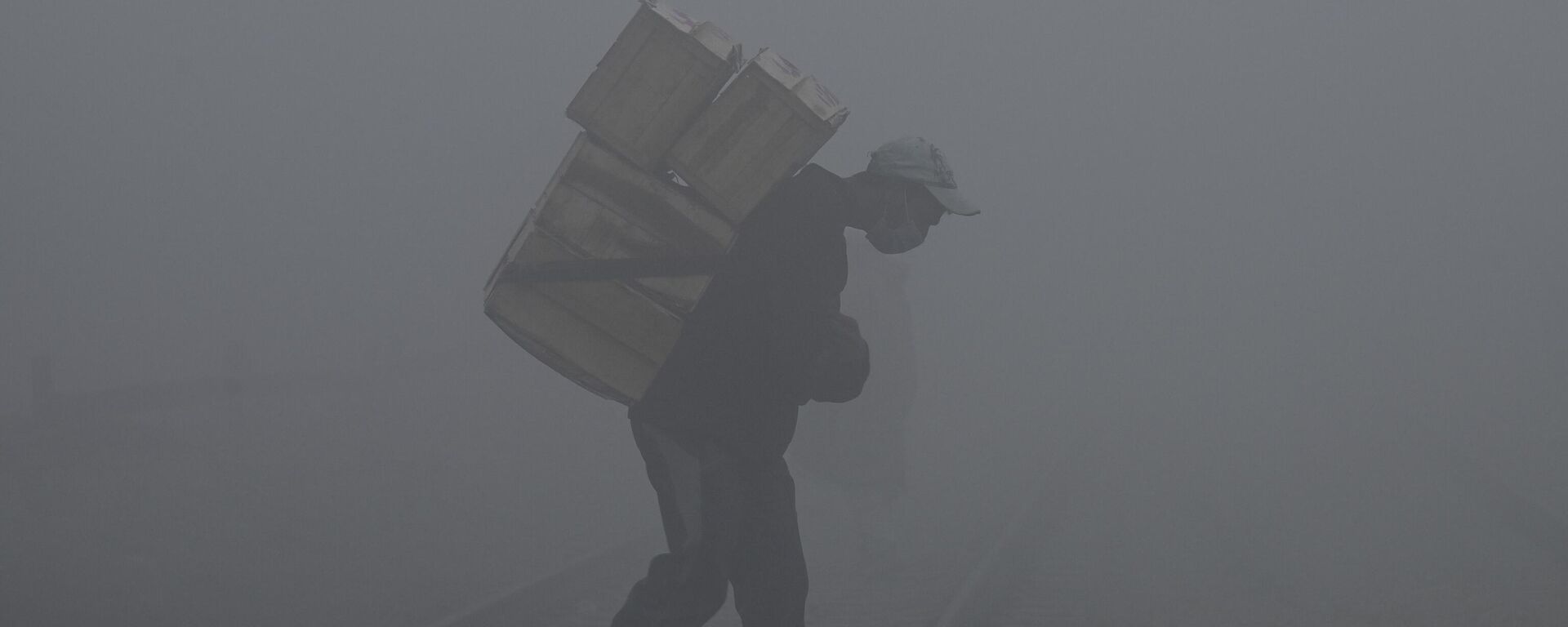 A labourer carries fruit boxes amid smoggy and foggy conditions early in the morning in Lahore on January 3, 2023. - Sputnik India, 1920, 13.03.2023