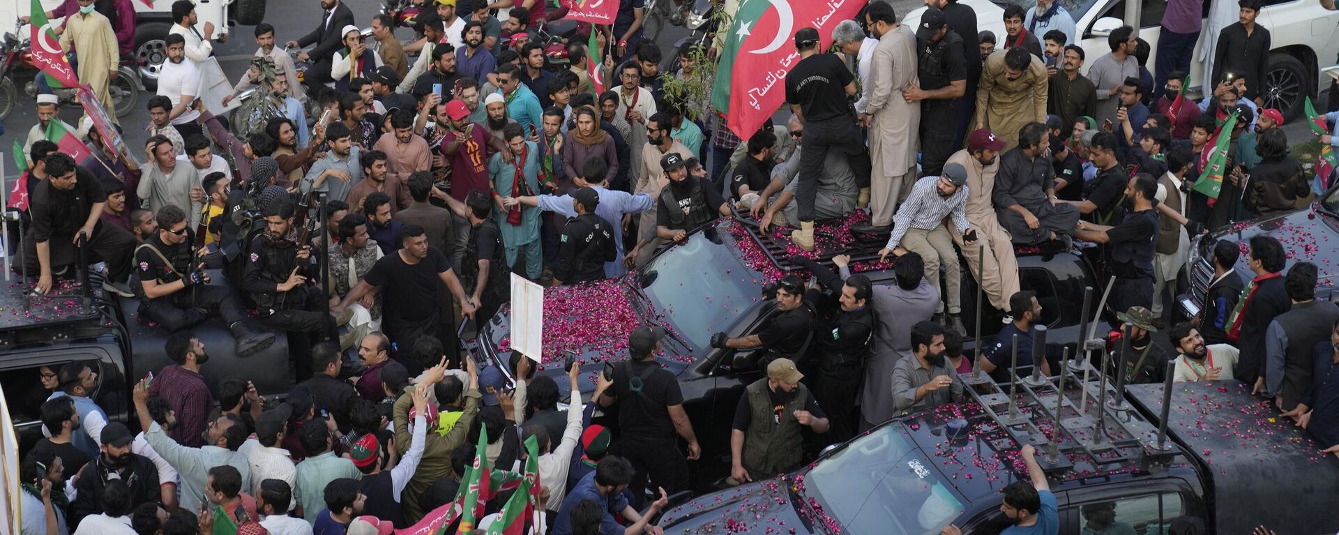 Security personnel and supporters move with a vehicle carrying Pakistan's former Prime Minister Imran Khan during an election campaign rally, in Lahore, Pakistan, Monday, March 13, 2023. - Sputnik India, 1920, 14.03.2023
