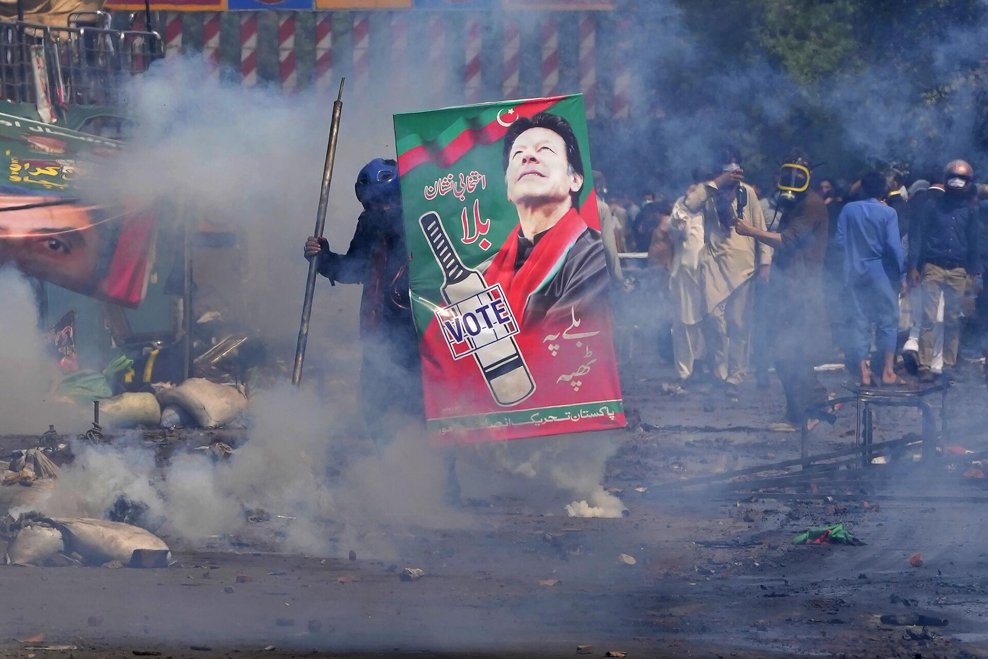 Supporters of former Prime Minister Imran Khan take cover after riot police officers fire tear gas to disperse them during clashes, in Lahore, Pakistan, Wednesday, March 15, 2023. - Sputnik India, 1920, 18.03.2023