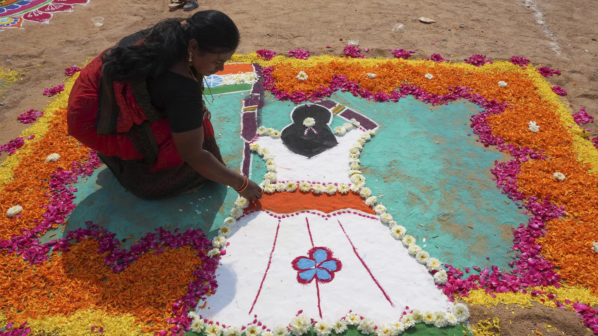 A woman prepares a Rangoli, a traditional art work of colored powder, during a rangoli competition on the eve of Makar Sankranti festival in Hyderabad, India, Friday, Jan. 13, 2023.