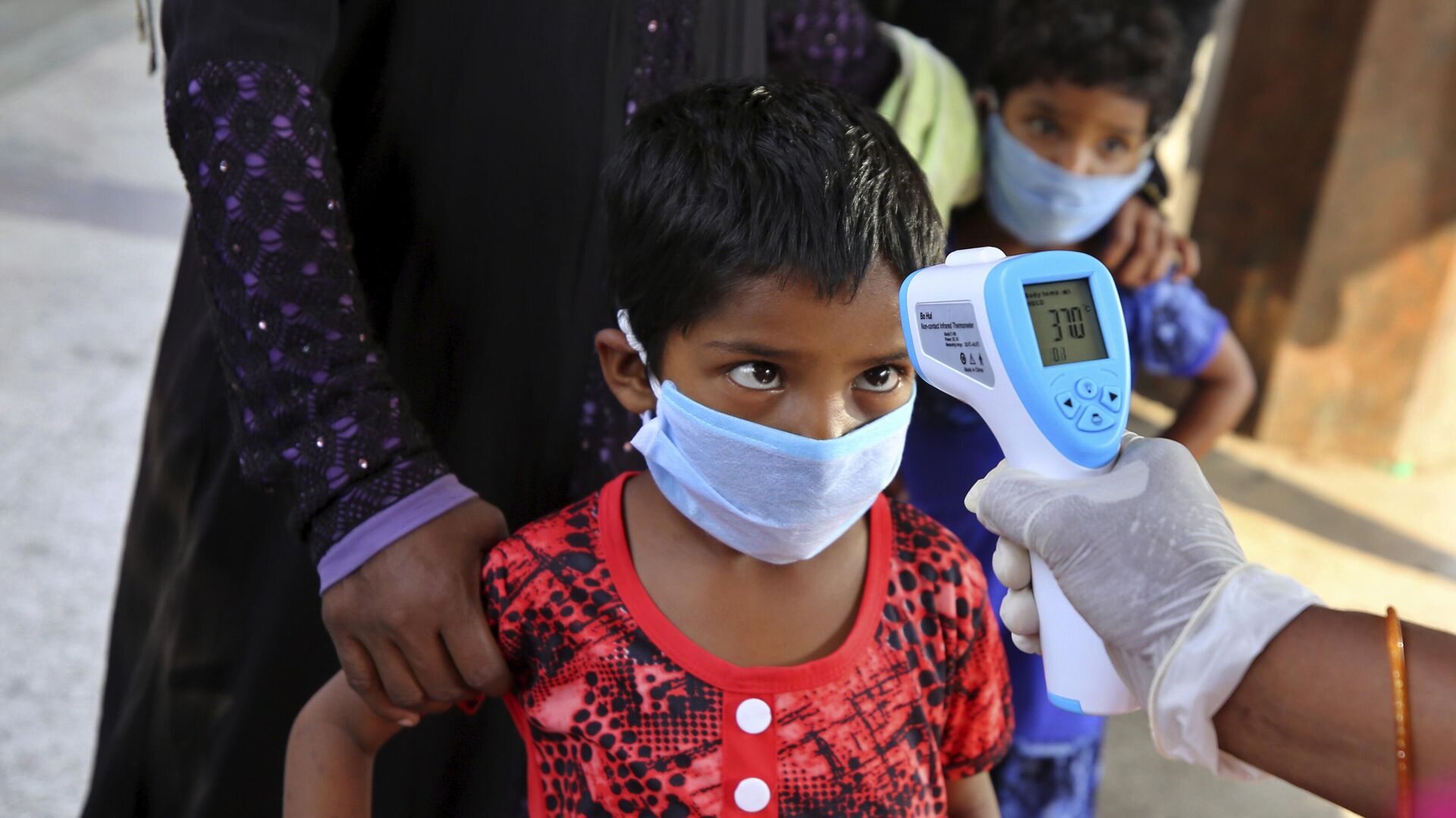 A health worker checks the temperature of a child, who had been stranded for weeks due to the lockdown to curb the spread of new coronavirus, before allowing her to board a bus in Bangalore, India, Wednesday, May 6, 2020, as the country partially relaxed its lockdown. - Sputnik India, 1920, 17.03.2023