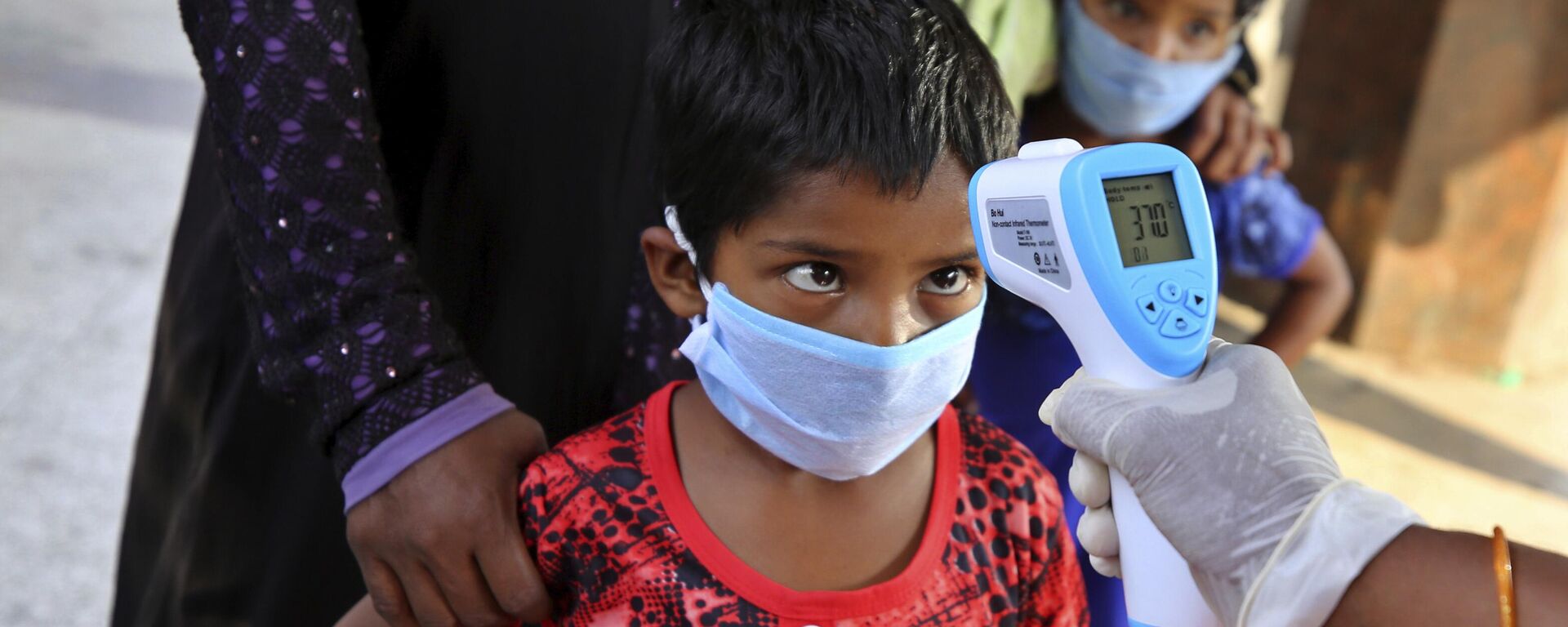 A health worker checks the temperature of a child, who had been stranded for weeks due to the lockdown to curb the spread of new coronavirus, before allowing her to board a bus in Bangalore, India, Wednesday, May 6, 2020, as the country partially relaxed its lockdown. - Sputnik India, 1920, 29.03.2023