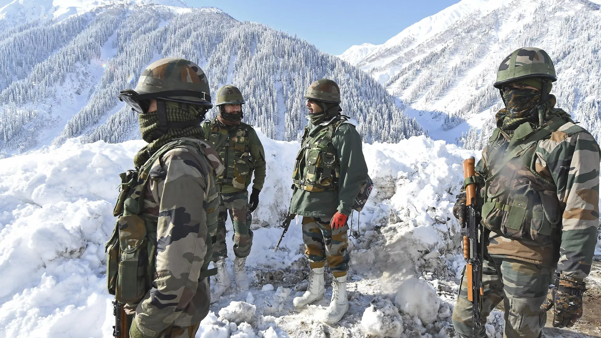 Indian army soldiers stand on a snow-covered road near Zojila mountain pass that connects Srinagar to the union territory of Ladakh, bordering China on February 28, 2021.