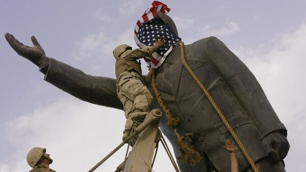 In this file photo taken Wednesday, April 9, 2003, an Iraqi man, bottom right, watches Cpl. Edward Chin of the 3rd Battalion, 4th Marines Regiment, cover the face of a statue of Saddam Hussein with an American flag before toppling the statue in downtown in Baghdad, Iraq. - Sputnik भारत