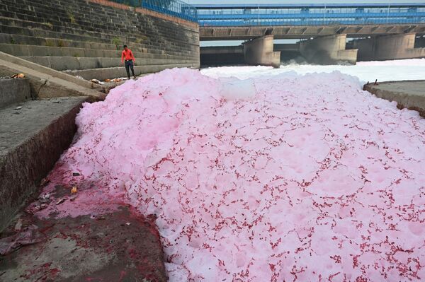 A man stands along the banks of river Yamuna coated with polluted foam in New Delhi on March 21, 2023. - Sputnik भारत