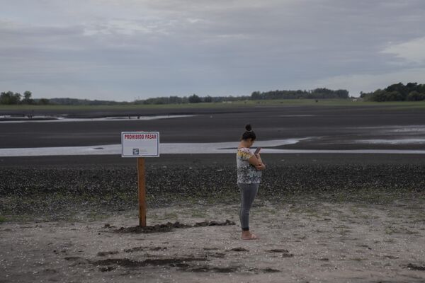 A woman take photos of the dried lakebed at the Canelon Grande dam that provides drinking water for the capital, ahead of World Water Day, in Canelones, Uruguay, Tuesday, March 21, 2023. - Sputnik भारत