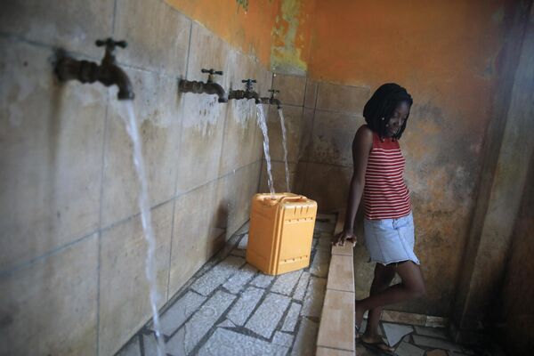A resident, without running water at home, fills a container at a water fill station, in Port-au-Prince, Haiti, Tuesday, March 21, 2023. - Sputnik भारत