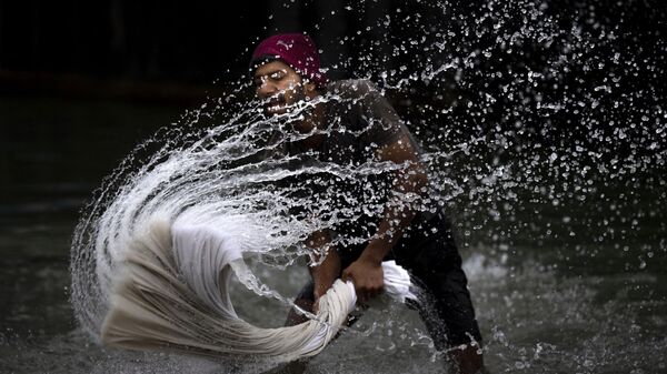 A washerman washes clothes on the banks of the river Brahmaputra on World Water Day in Guwahati, India, Wednesday, March 22, 2023. - Sputnik भारत
