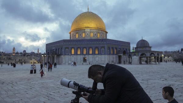 A man observes the moon through a telescope next to the Dome of Rock Mosque at the Al-Aqsa Mosque compound in Jerusalem's Old City, Tuesday, March 21, 2023. - Sputnik India