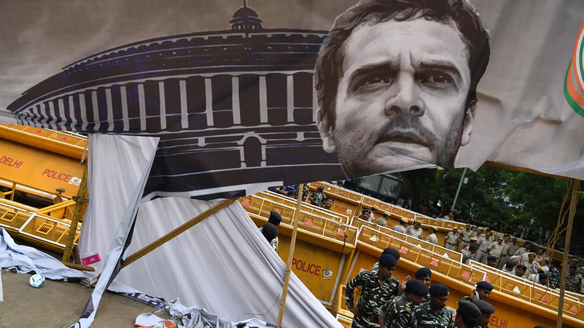 In this file photo taken on August 8, 2018 policemen stand near a partially torn banner with an image of India's Congress Party leader Rahul Gandhi, after a protest by the National Students Union of India (NSUI)ю