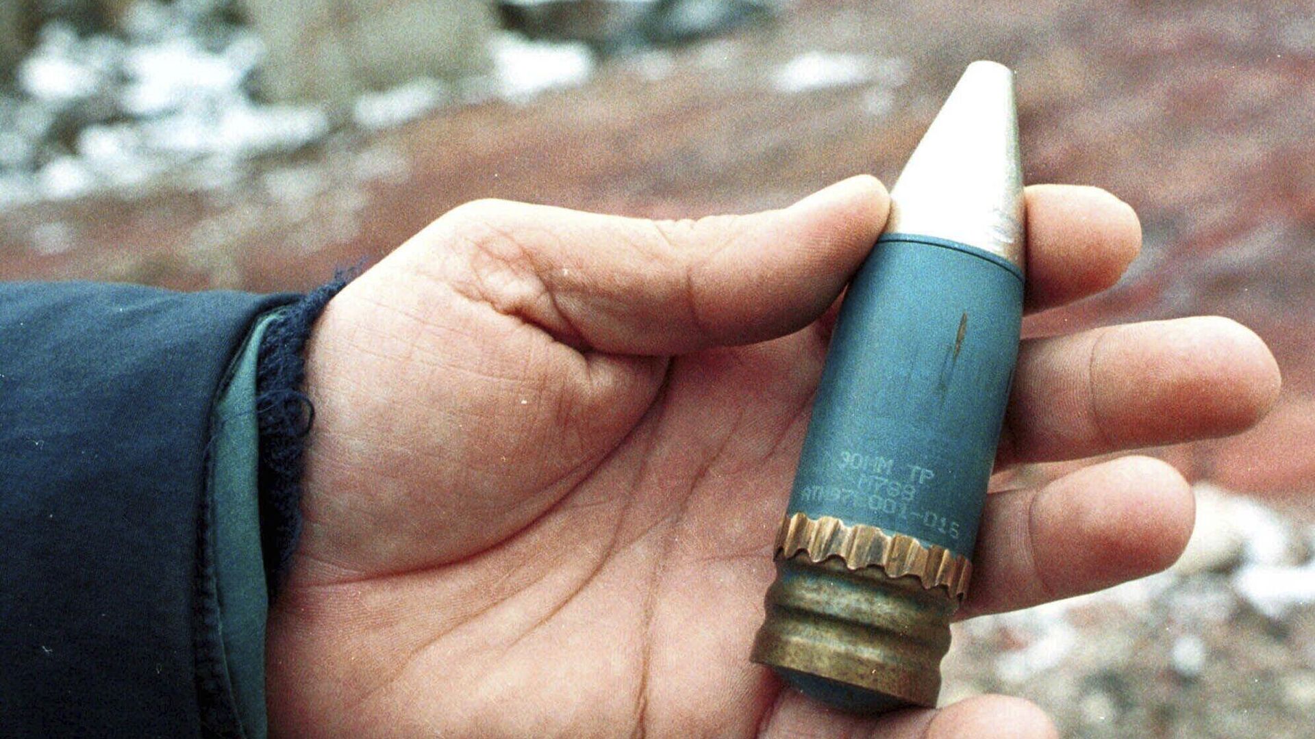 A member of a radiation team holds a 30mm armor-piercing shell containing depleted uranium, used by NATO during air strikes on Bosnia in 1995, which was found in a former military factory in the suburb of Vogosca, near Sarajevo, Jan. 15, 2001. - Sputnik भारत, 1920, 08.09.2023