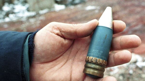 A member of a radiation team holds a 30mm armor-piercing shell containing depleted uranium, used by NATO during air strikes on Bosnia in 1995, which was found in a former military factory in the suburb of Vogosca, near Sarajevo, Jan. 15, 2001. - Sputnik भारत