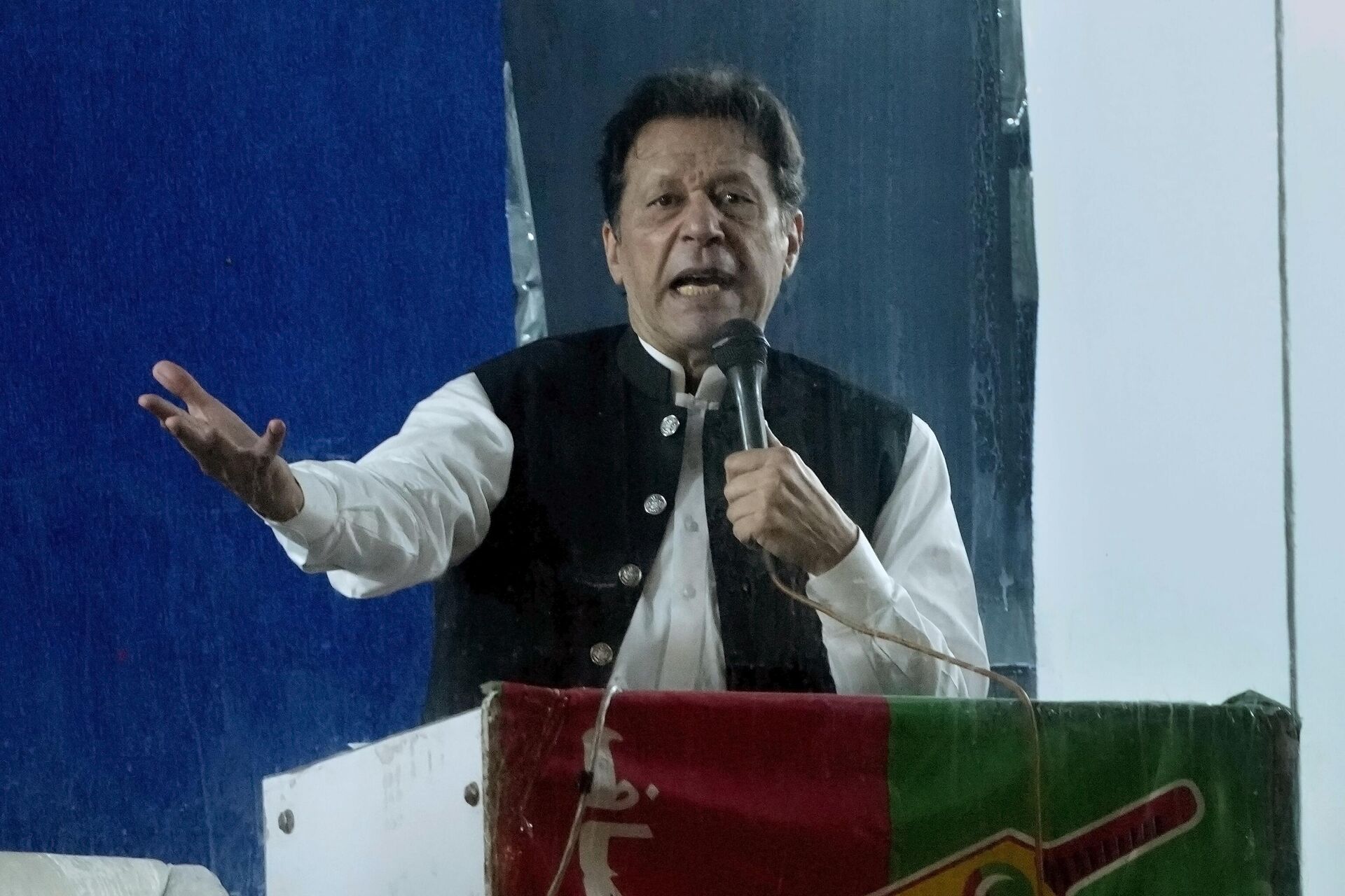 Protected by a bulletproof barrier, former Prime Minister Imran Khan speaks during a rally in Lahore, Pakistan, Sunday, March 26, 2023, to pressure the government of Shahbaz Sharif to agree to hold snap elections. - Sputnik India, 1920, 02.02.2024