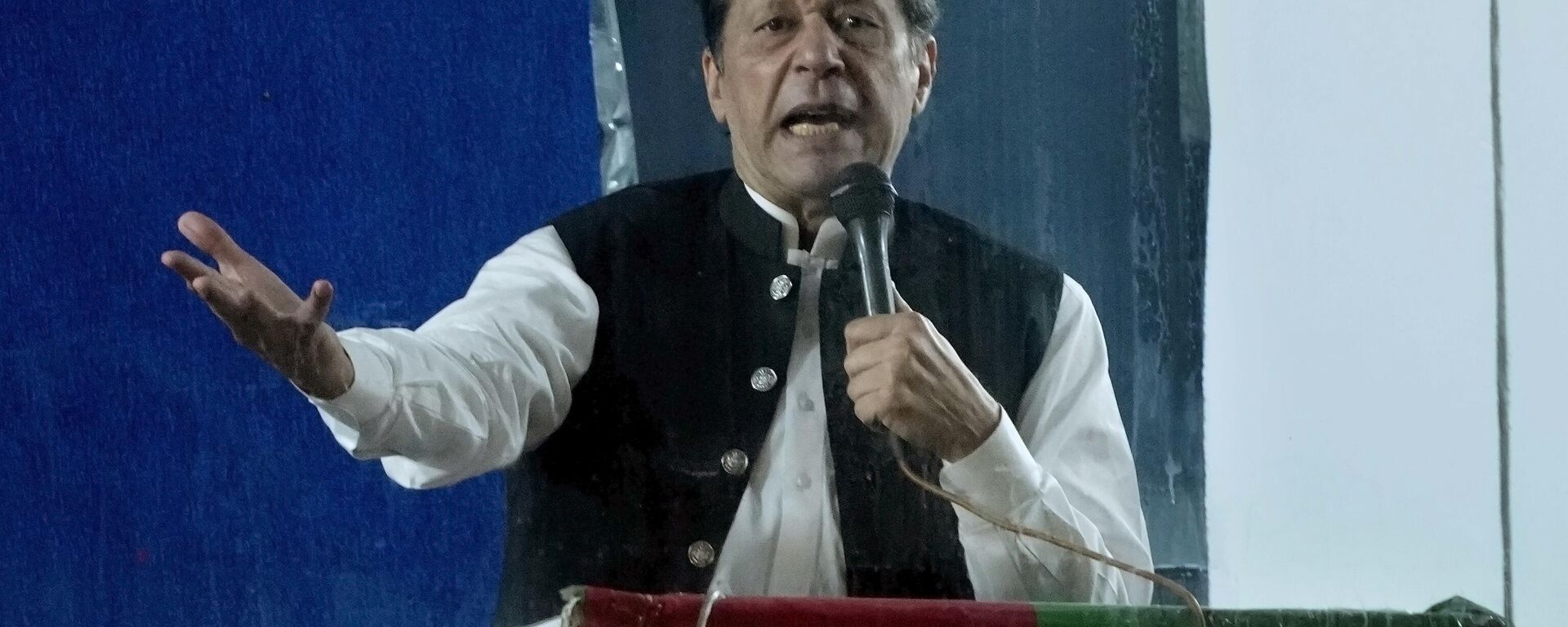 Protected by a bulletproof barrier, former Prime Minister Imran Khan speaks during a rally in Lahore, Pakistan, Sunday, March 26, 2023, to pressure the government of Shahbaz Sharif to agree to hold snap elections. - Sputnik भारत, 1920, 18.05.2023