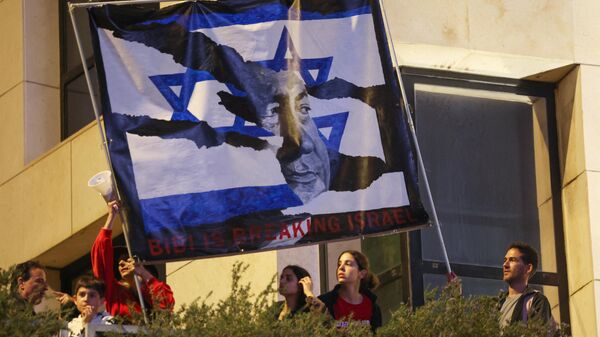 Israeli protesters lift a banner depicting Prime Minister Benjamin Netanyahu during a rally against the government's controversial judicial overhaul bill in Tel Aviv, on March 25, 2023.  - Sputnik भारत