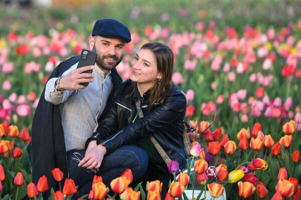 A couple poses for pictures in a field of &quot;Tulipani Italiani&quot; tulips in Arese, near Milan, Italy on March 25, 2023. - Over 600.000 tulips were planted by the Dutch couple Edwin Koeman and Nitsuje Wolanios. (Photo by Piero CRUCIATTI / AFP) - Sputnik India