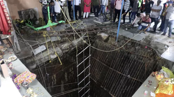 People stand around a structure built over an old temple well that collapsed Thursday - Sputnik भारत