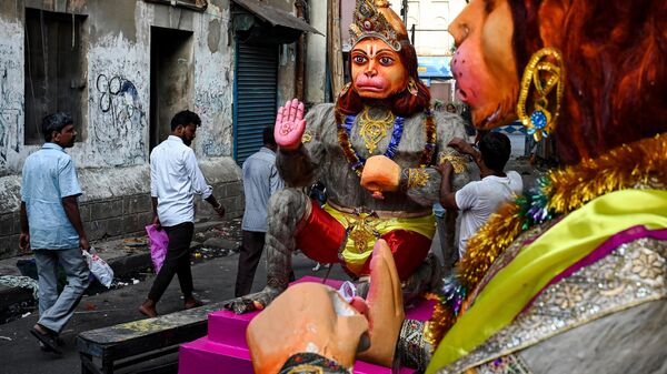 Pedestrians pass as an artisan (R) gives finishing touches to a statue of Hindu god, Lord Hanuman ahead of the Hanuman Jayanti festival, at a workshop along a road in Kolkata on April 5, 2023. - Sputnik India