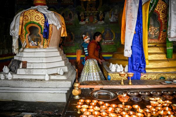 A woman along with an infant offers prayers at the Tawang monastery in Tawang, a town in the northeast Indian state of Arunachal Pradesh on April 5, 2023. (Photo by Arun SANKAR / AFP) - Sputnik India
