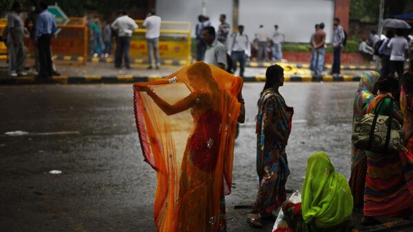 An Indian woman adjusts her sari after she got wet in the monsoon rains in New Delhi, India, Wednesday, Aug. 7, 2013 - Sputnik India
