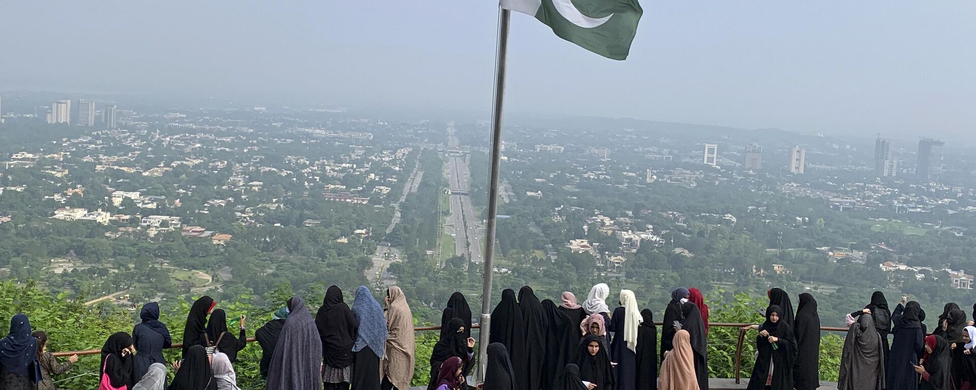 A Pakistani flag flies on a lookout as women take in the view of Islamabad, Pakistan, Wednesday, July 27, 2022. - Sputnik India, 1920, 10.11.2023
