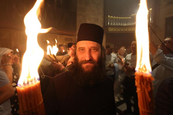 पवित्र अग्नि दिखाई देने की परंपरा 11 सदियों से एक ही रूप में मनाया जाता है (Photo by Menahem KAHANA / AFP) - Sputnik भारत