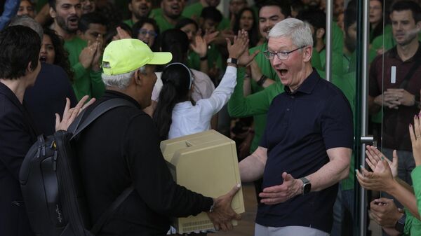 Apple CEO Tim Cook, right, reacts after seeing an old old Macintosh Classic machine brought by a visitor during the opening of the first Apple Inc. flagship store in Mumbai, India, Tuesday, April 18, 2023. - Sputnik India