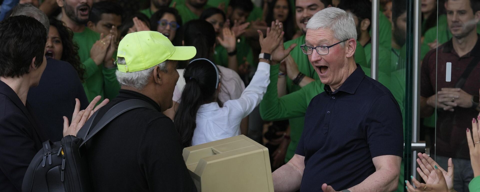 Apple CEO Tim Cook, right, reacts after seeing an old old Macintosh Classic machine brought by a visitor during the opening of the first Apple Inc. flagship store in Mumbai, India, Tuesday, April 18, 2023. - Sputnik India, 1920, 18.04.2023