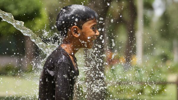 A boy cools himself under an irrigation water pipe  as northern Indian continues to reel under intense heat wave in Lucknow in the the Indian state of Uttar Pradesh, Wednesday, April 19, 2023. - Sputnik भारत