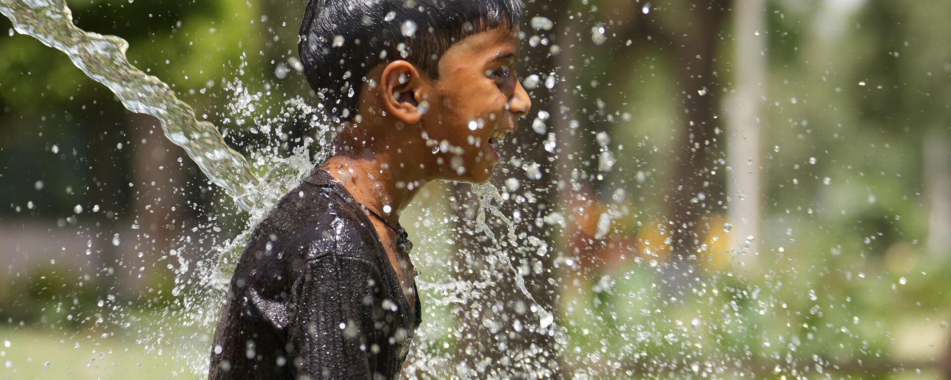 A boy cools himself under an irrigation water pipe  as northern Indian continues to reel under intense heat wave in Lucknow in the the Indian state of Uttar Pradesh, Wednesday, April 19, 2023. - Sputnik India, 1920, 19.04.2023
