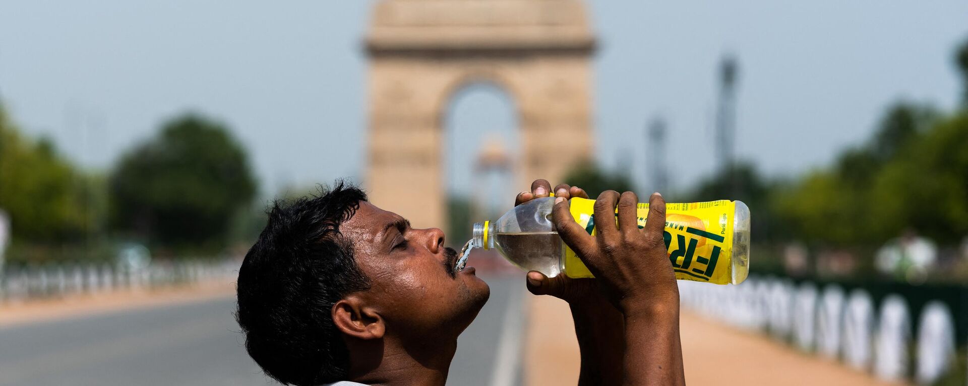 A worker quenches his thirst with water from a bottle taking a break from cleaning weeds from a park near India Gate amid rising temperatures in New Delhi on May 27, 2020. - Sputnik India, 1920, 05.07.2023