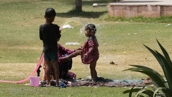 A family cools themself in a park using irrigation water pipe  as northern Indian continues to reel under intense heatwave in Lucknow in the the Indian state of Uttar Pradesh, Wednesday, April 19, 2023. - Sputnik India