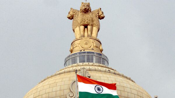 The Indian national flag flies in front of the Indian national emblem, lying atop the Vidhana Soudha State assembly in Bangalore - Sputnik India