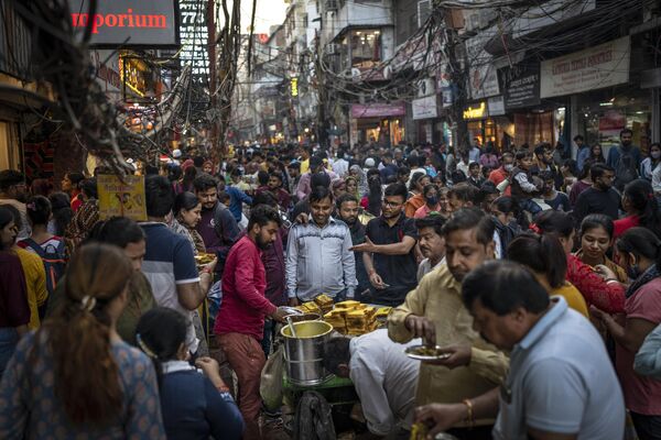 People eat street food as shoppers crowd a market in New Delhi, India, Saturday, Nov. 12, 2022. - Sputnik India