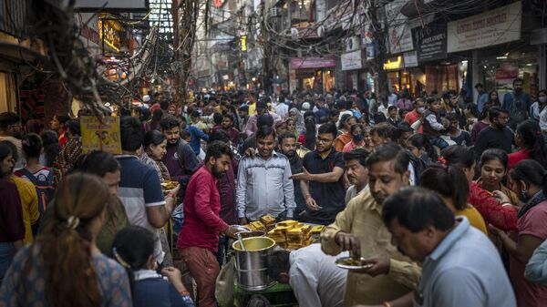 People eat street food as shoppers crowd a market in New Delhi, India, Saturday, Nov. 12, 2022. - Sputnik India