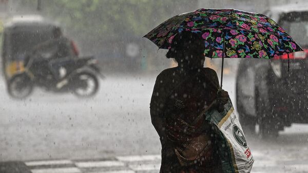 A woman holds an umbrella as she walks along a road during a heavy monsoon rainfall in Chennai  - Sputnik भारत