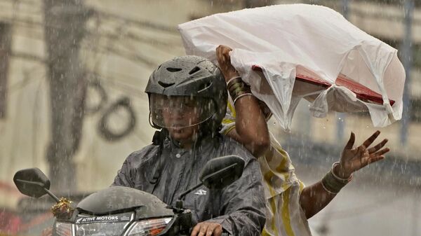 Две женщины едут на скутере во время предмусонных дождей в Хайдарабаде, Индия - Sputnik भारत