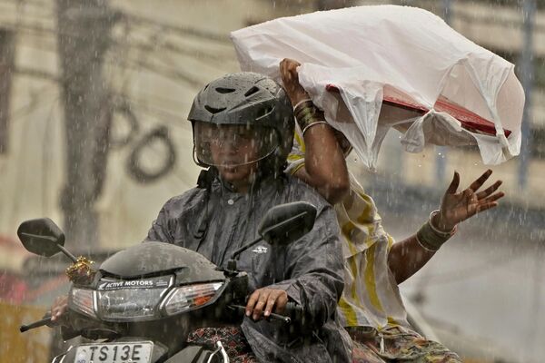 Two women ride on a scooter during pre-monsoon rains in Hyderabad, India, Monday, May 1, 2023. - Sputnik India